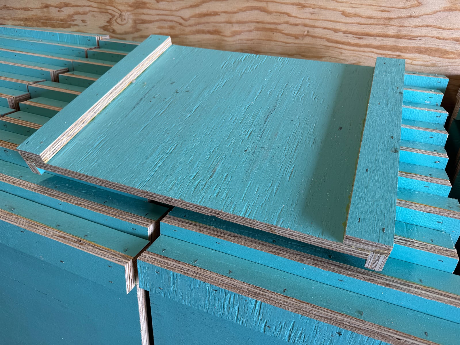 Locally built painted 10-frame migratory covers stacked in the Bee To Z workshop
